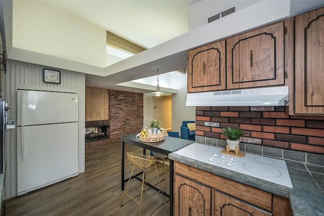 kitchen featuring brown cabinets, freestanding refrigerator, visible vents, dark wood-style flooring, and under cabinet range hood