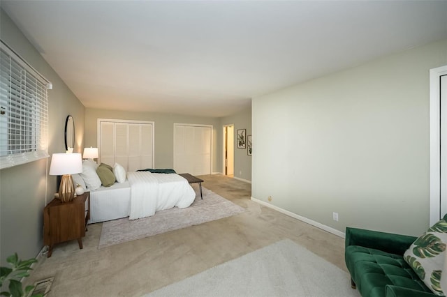 bedroom with light carpet, baseboards, and multiple closets