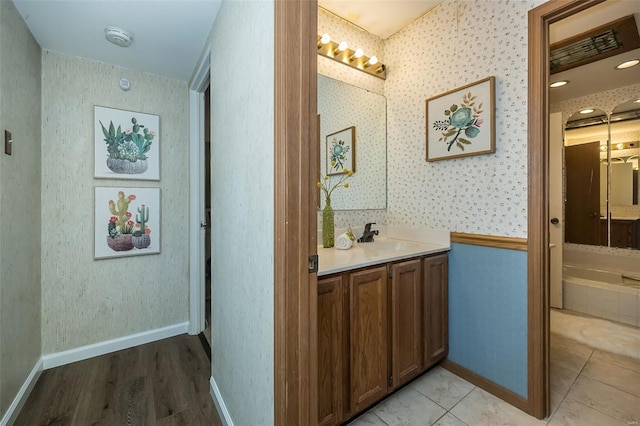 hallway with a sink, wallpapered walls, and light wood-style floors