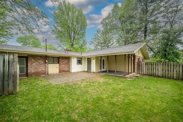 back of house with a lawn, a patio area, brick siding, and fence
