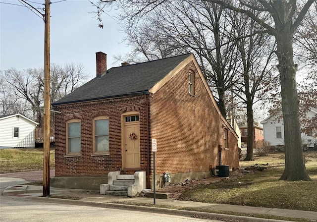 view of front of house with a chimney, central AC unit, brick siding, a shingled roof, and entry steps