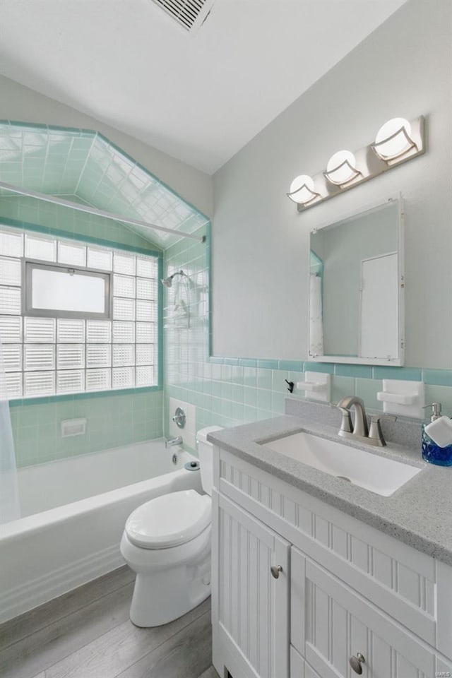 full bathroom featuring wood finished floors,  shower combination, tile walls, toilet, and visible vents