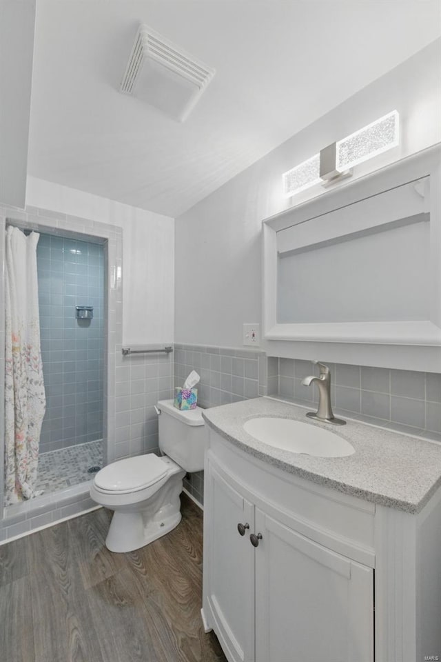 bathroom with wood finished floors, a stall shower, vanity, toilet, and visible vents