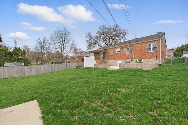 back of property with brick siding, a yard, and a fenced backyard