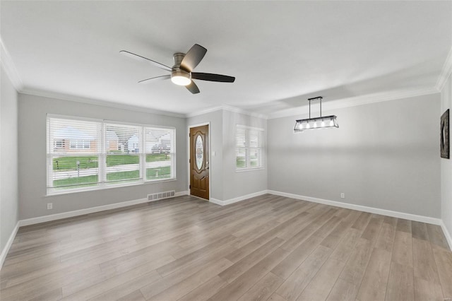 spare room with a ceiling fan, ornamental molding, light wood-style floors, and visible vents
