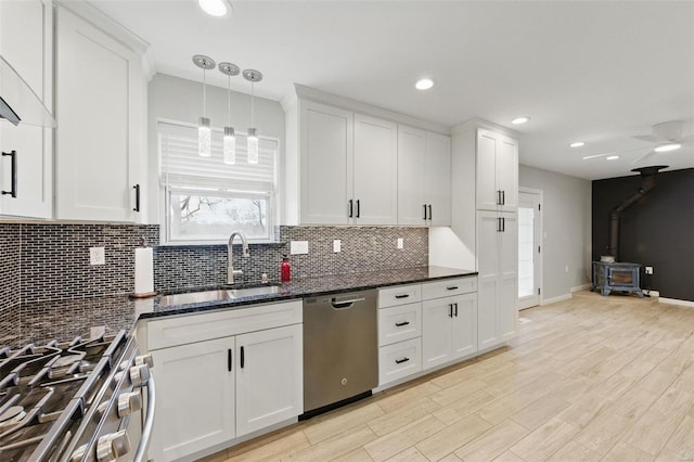kitchen featuring white cabinets, stainless steel appliances, a wood stove, and tasteful backsplash