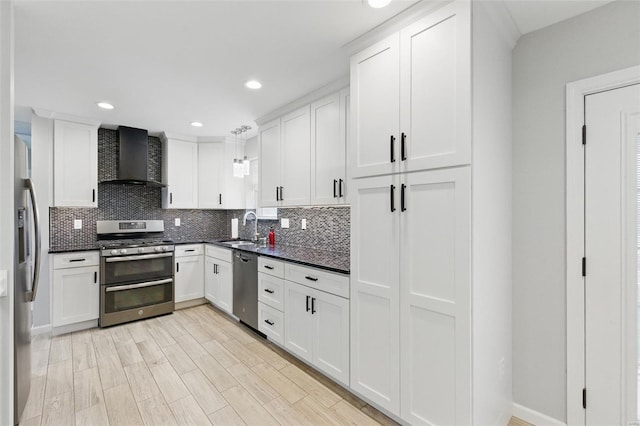 kitchen with a sink, white cabinetry, decorative backsplash, wall chimney range hood, and appliances with stainless steel finishes