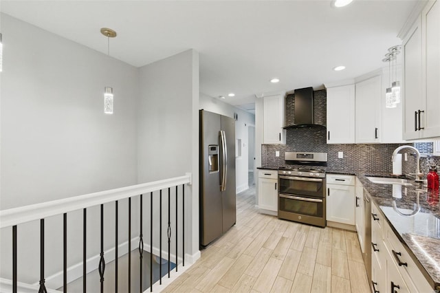 kitchen featuring wall chimney exhaust hood, stainless steel appliances, a sink, tasteful backsplash, and white cabinetry