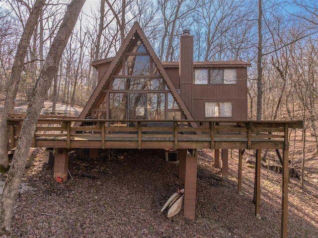 rear view of property featuring a wooden deck and a chimney