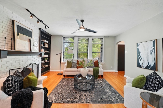 living area featuring track lighting, arched walkways, ceiling fan, and wood finished floors