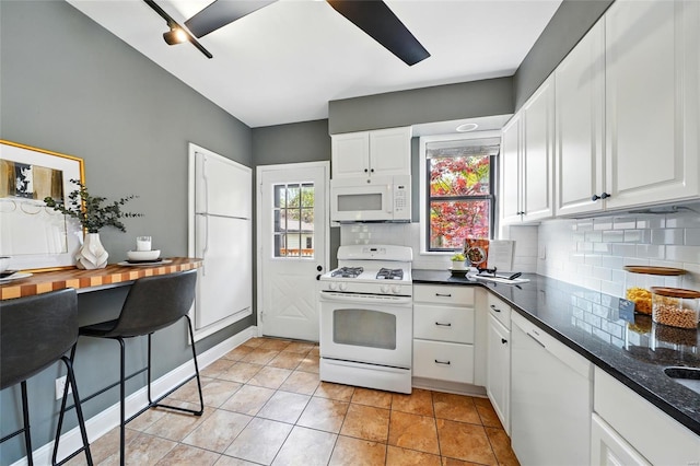kitchen with white cabinetry, light tile patterned floors, white appliances, and tasteful backsplash
