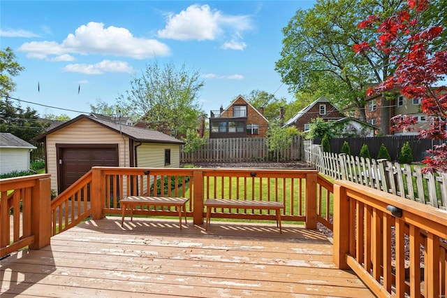 wooden deck featuring a detached garage, a residential view, fence, and an outbuilding