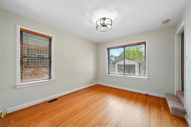 unfurnished room with baseboards, wood finished floors, and visible vents