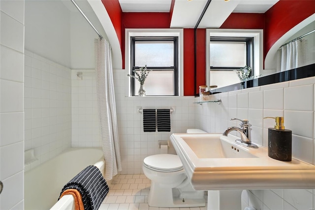 bathroom featuring tile patterned flooring, shower / bath combo with shower curtain, toilet, and tile walls