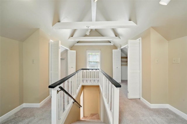 interior space with baseboards, lofted ceiling with beams, and light carpet
