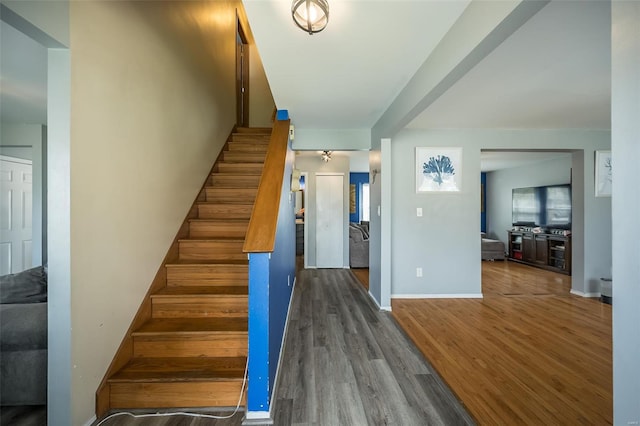 staircase featuring baseboards and wood finished floors