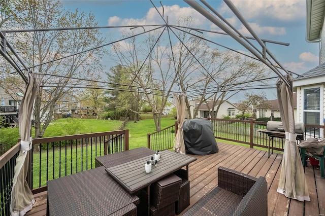 wooden deck featuring a yard, outdoor dining space, and a grill