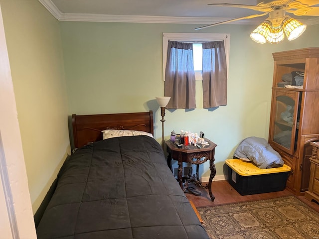 bedroom with baseboards, crown molding, and wood finished floors