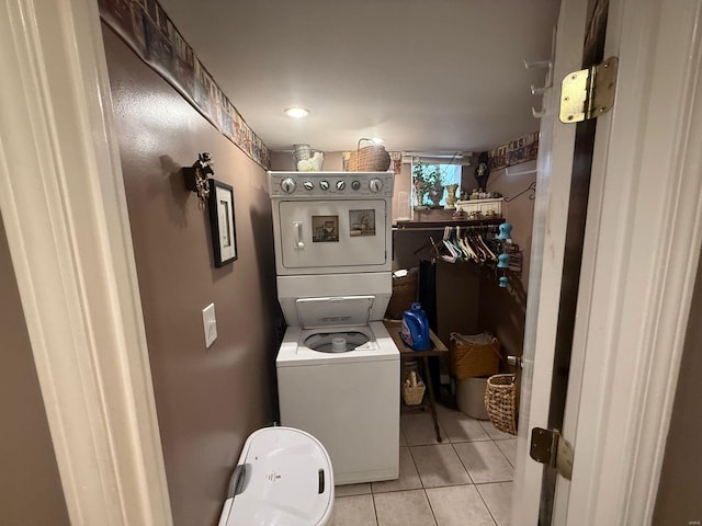 laundry area featuring tile patterned floors, stacked washer / drying machine, and laundry area