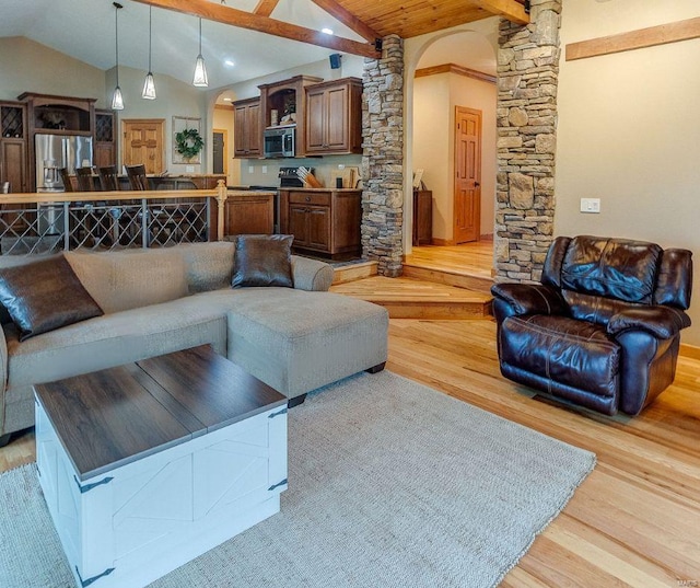 living room featuring light wood-type flooring, lofted ceiling with beams, ornate columns, and arched walkways