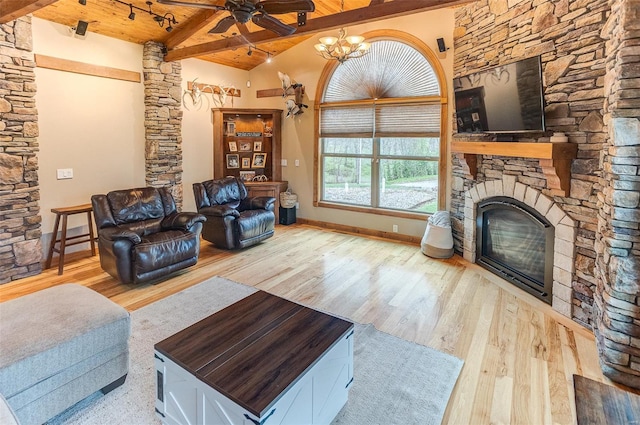 living room featuring wood finished floors, a stone fireplace, vaulted ceiling with beams, and wood ceiling