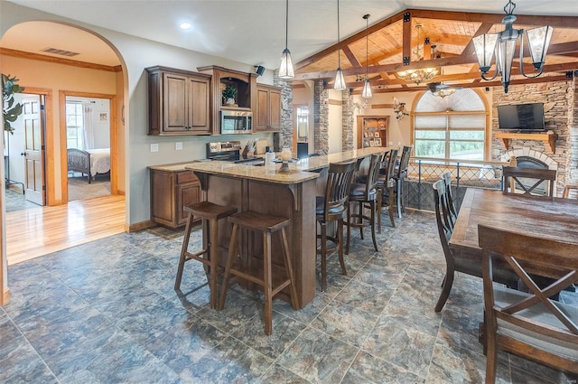kitchen featuring open shelves, appliances with stainless steel finishes, a center island, a kitchen breakfast bar, and lofted ceiling
