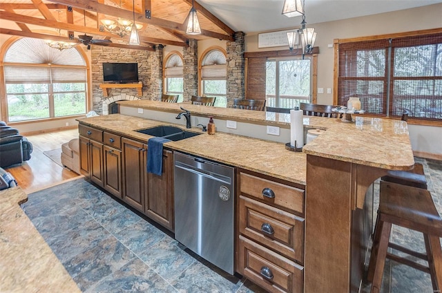 kitchen with a sink, vaulted ceiling with beams, decorative light fixtures, stainless steel dishwasher, and open floor plan