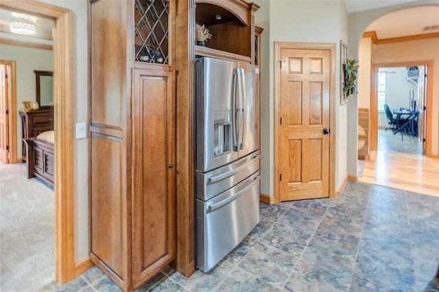 kitchen featuring stainless steel fridge, open shelves, visible vents, baseboards, and arched walkways