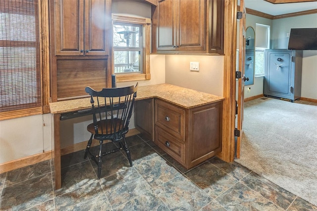 home office with dark carpet, baseboards, crown molding, and built in study area