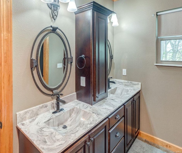 bathroom featuring double vanity, a sink, and baseboards