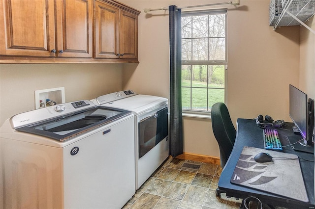 clothes washing area featuring baseboards, cabinet space, separate washer and dryer, and stone finish floor