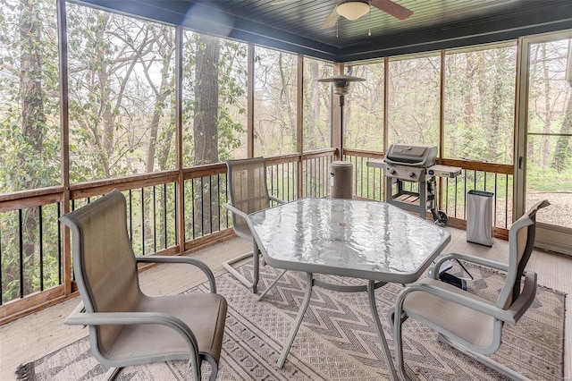 sunroom featuring a healthy amount of sunlight, outdoor dining space, and a ceiling fan