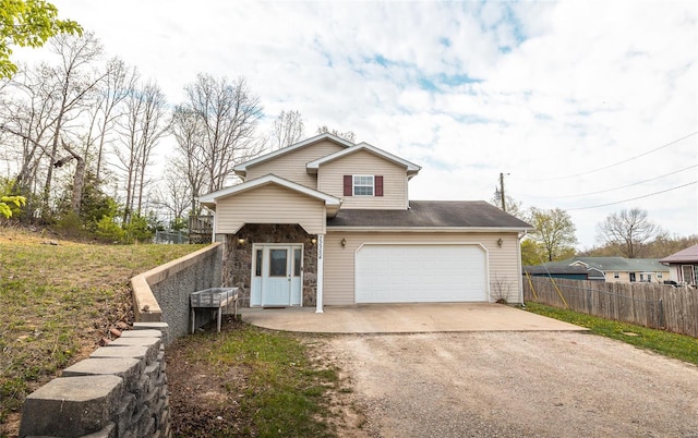 traditional-style home featuring driveway, stone siding, and fence