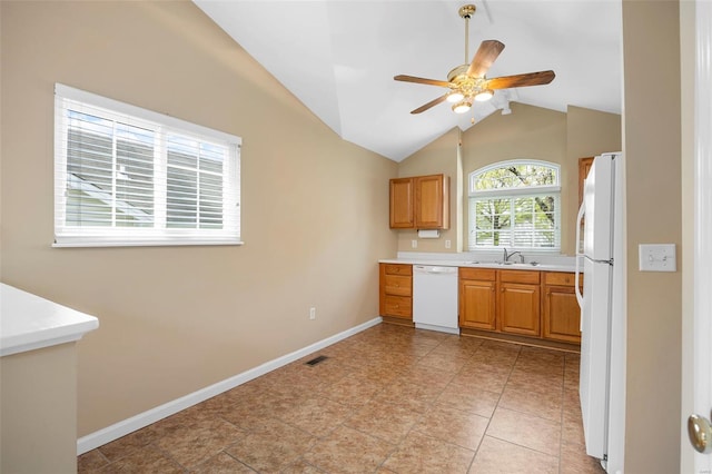 kitchen with lofted ceiling, white appliances, ceiling fan, light countertops, and a sink