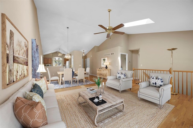 living area with visible vents, a ceiling fan, wood finished floors, and vaulted ceiling with skylight