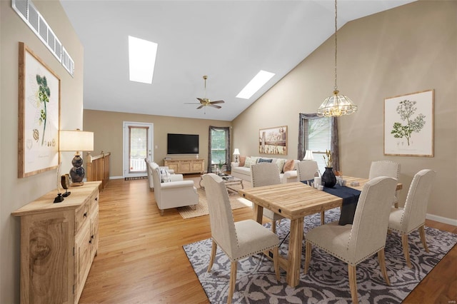 dining area featuring a skylight, a notable chandelier, light wood-type flooring, and a wealth of natural light