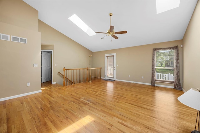 interior space featuring a skylight, high vaulted ceiling, light wood finished floors, and visible vents