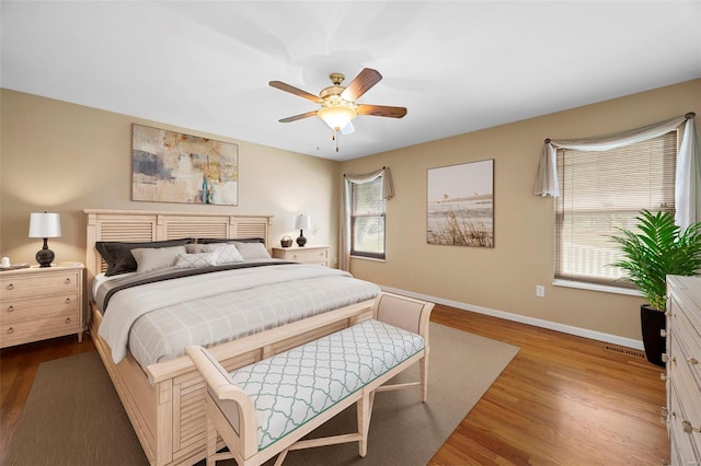 bedroom with a ceiling fan, baseboards, visible vents, and wood finished floors