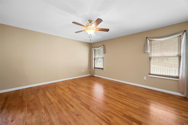 spare room with baseboards and light wood finished floors