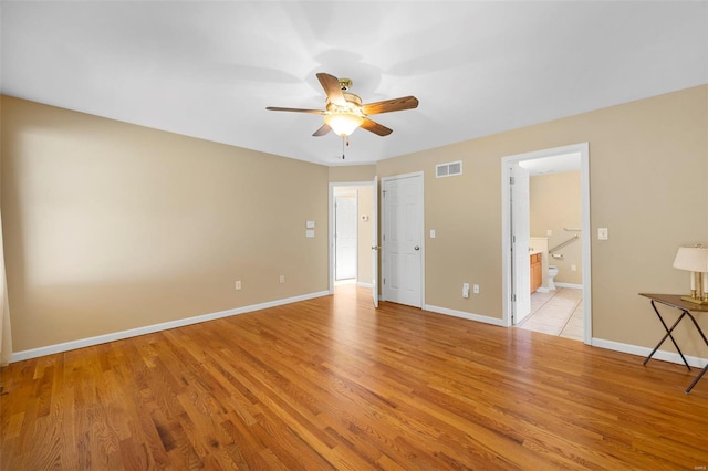 unfurnished bedroom featuring light wood-style floors, baseboards, ensuite bath, and visible vents