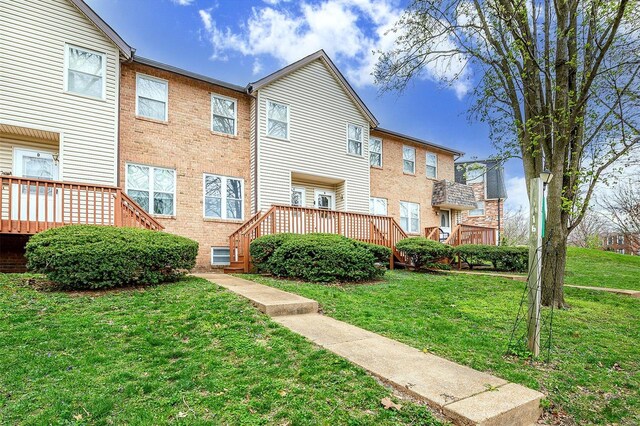 back of property featuring a deck, brick siding, and a yard