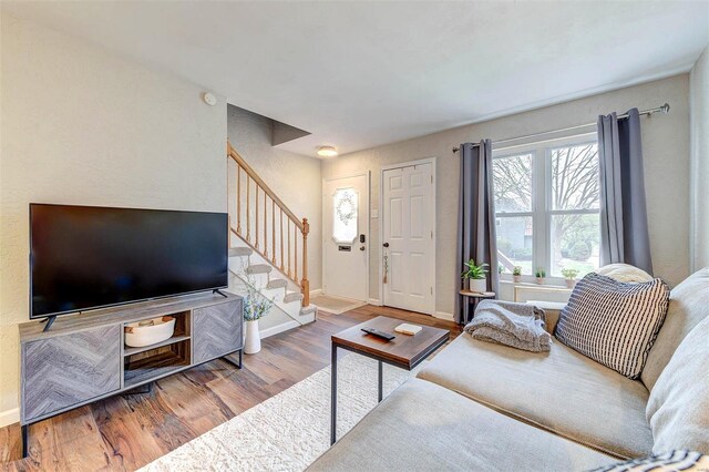 living room with baseboards, stairs, and wood finished floors
