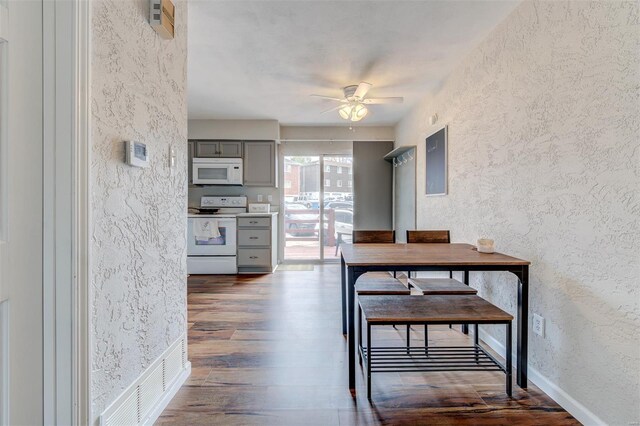 dining space with dark wood finished floors, baseboards, ceiling fan, and a textured wall