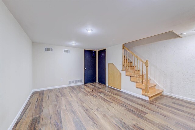finished basement featuring stairs, visible vents, wood finished floors, and baseboards