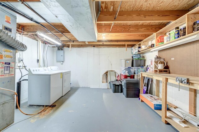 unfinished basement with a workshop area, washing machine and dryer, and electric panel