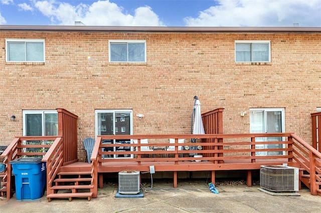 back of house with brick siding, central AC, and a wooden deck