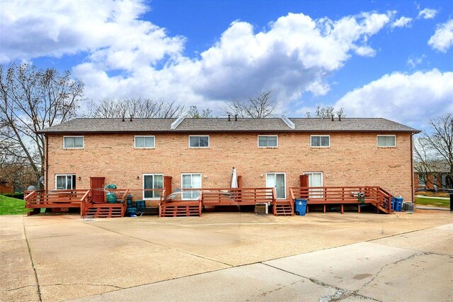 back of house featuring a patio, brick siding, and a deck