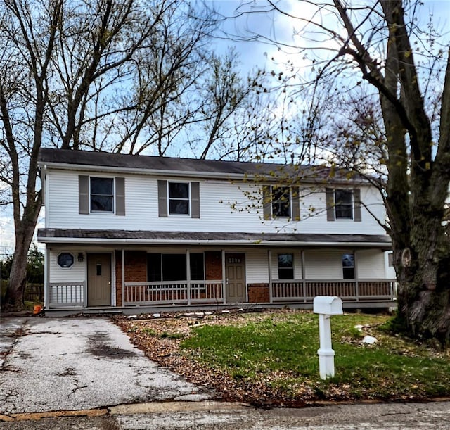 view of front facade featuring brick siding, aphalt driveway, and covered porch