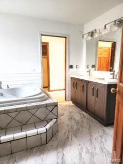 bathroom featuring a relaxing tiled tub and vanity
