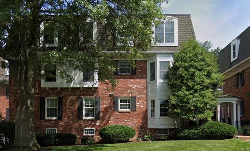 view of front of home with brick siding and a front lawn